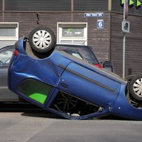 Foto: Auto sadursmē Rīgā spēkrats apgāzies uz jumta
