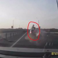 Video: Motociklists pēc avārijas paliek uz braucoša auto jumta