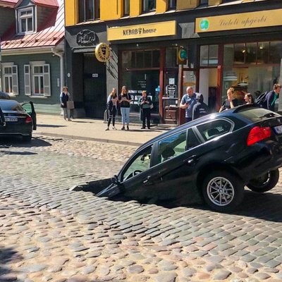 Foto: Ģertrūdes ielas bruģī ielūzis BMW; 'Rīgas siltums' uzņemas atbildību