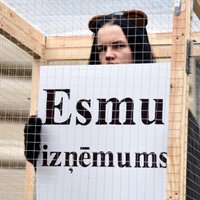 Foto: Cilvēks būrī pie Saeimas protestē pret dzīvnieku izmantošanu cirkā
