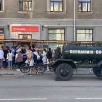 Foto: Daugavpilī pie bankām rindās stāvošajiem nodrošina soliņus un ūdensmašīnu